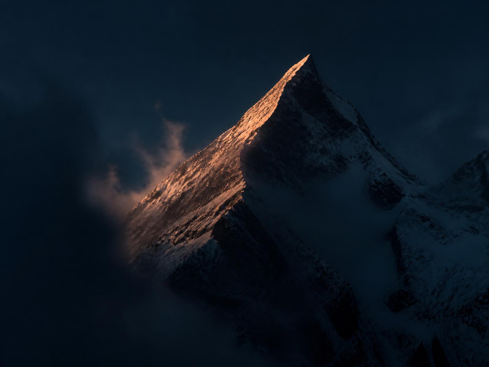 Snow-capped mountain peak lit by first light